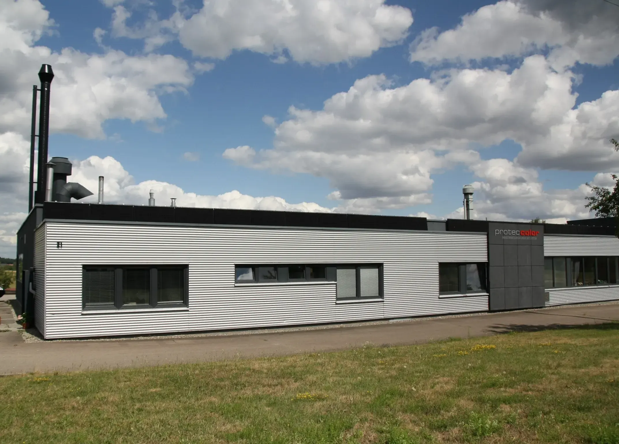 Das Betriebsgebäude von Proteccolor in Pfalzgrafenweiler mit Firmenlogo an der Fassade.
