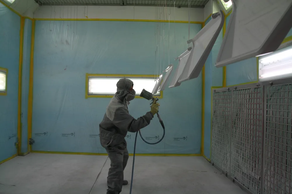 Levin Weinläder lackiert hängende Bauteile in der Lackierkabine von Proteccolor.