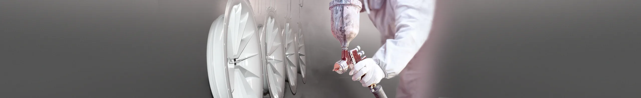 Nasslackierung bei Proteccolor: Lackierer mit Spritzpistole und frisch beschichtete Ventilatorräder.